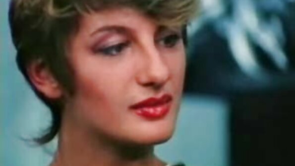 En brunett Latina med tatueringar på kroppen tränger in i hennes säng